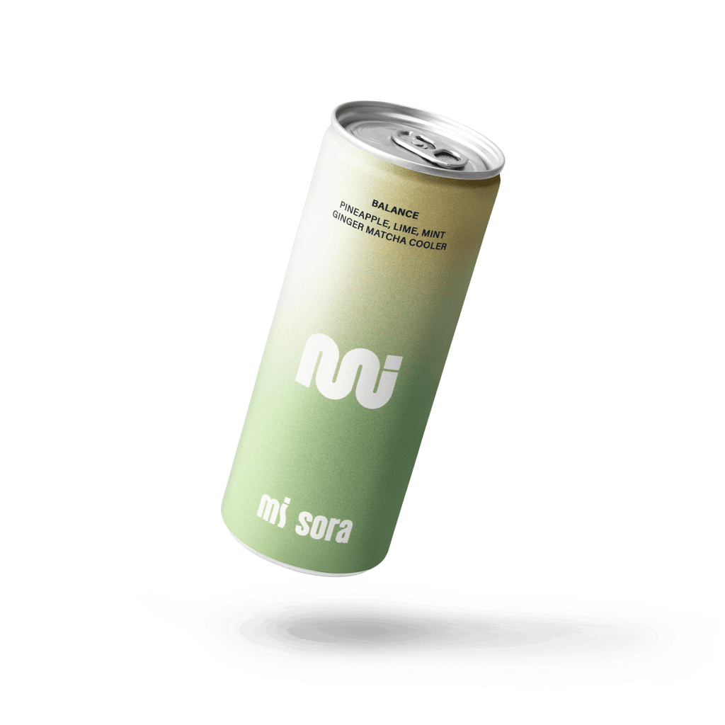 A single can of mi sora Balance ginger matcha cooler floating above a white liquid splash on a solid black background.